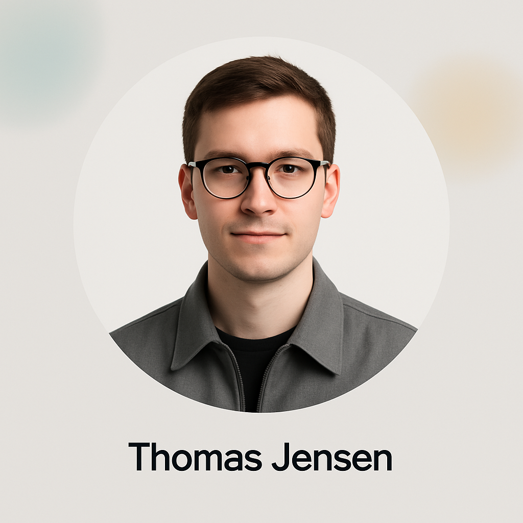 Portrait of Thomas Jensen, a young man with short brown hair and glasses, wearing a gray jacket