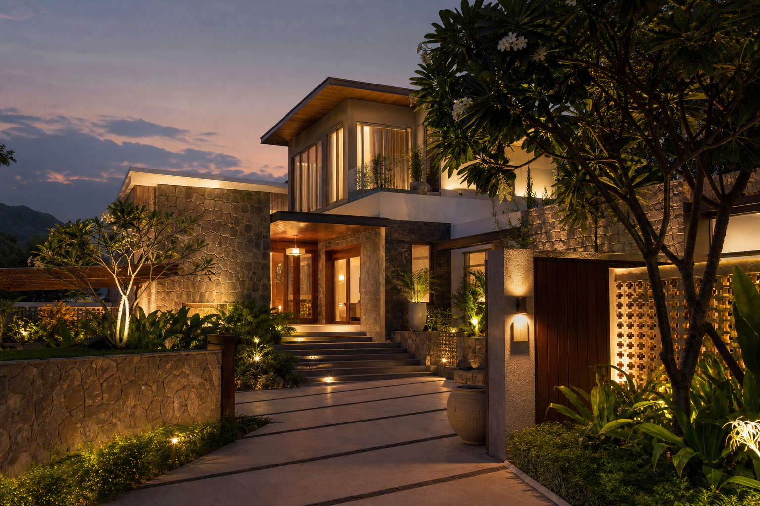 Twilight view of a premium villa exterior with warm ambient lighting, landscaped garden, and a welcoming entry path prepared for arriving guests