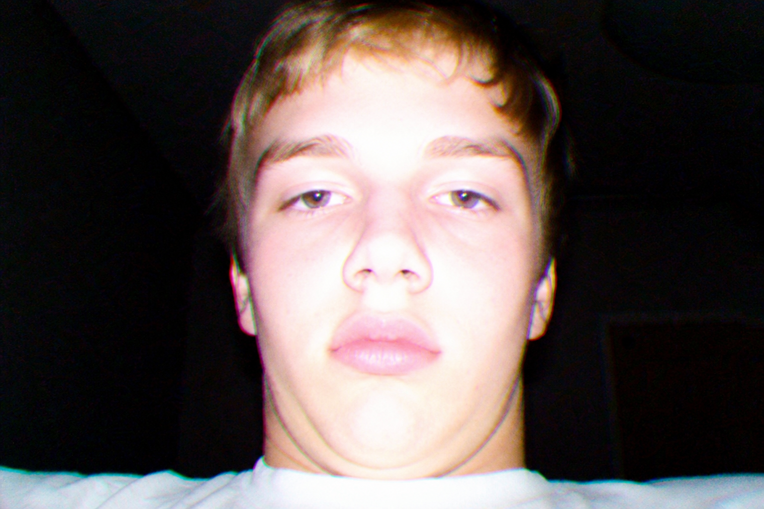 Awkward close-up portrait of a friend, overexposed and badly lit, framed like a cheap webcam snapshot