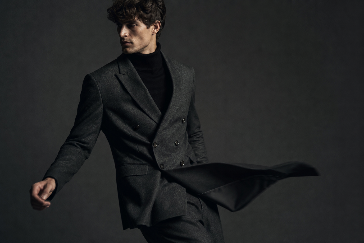 Model in a charcoal suit captured mid-turn with controlled motion blur on fabric