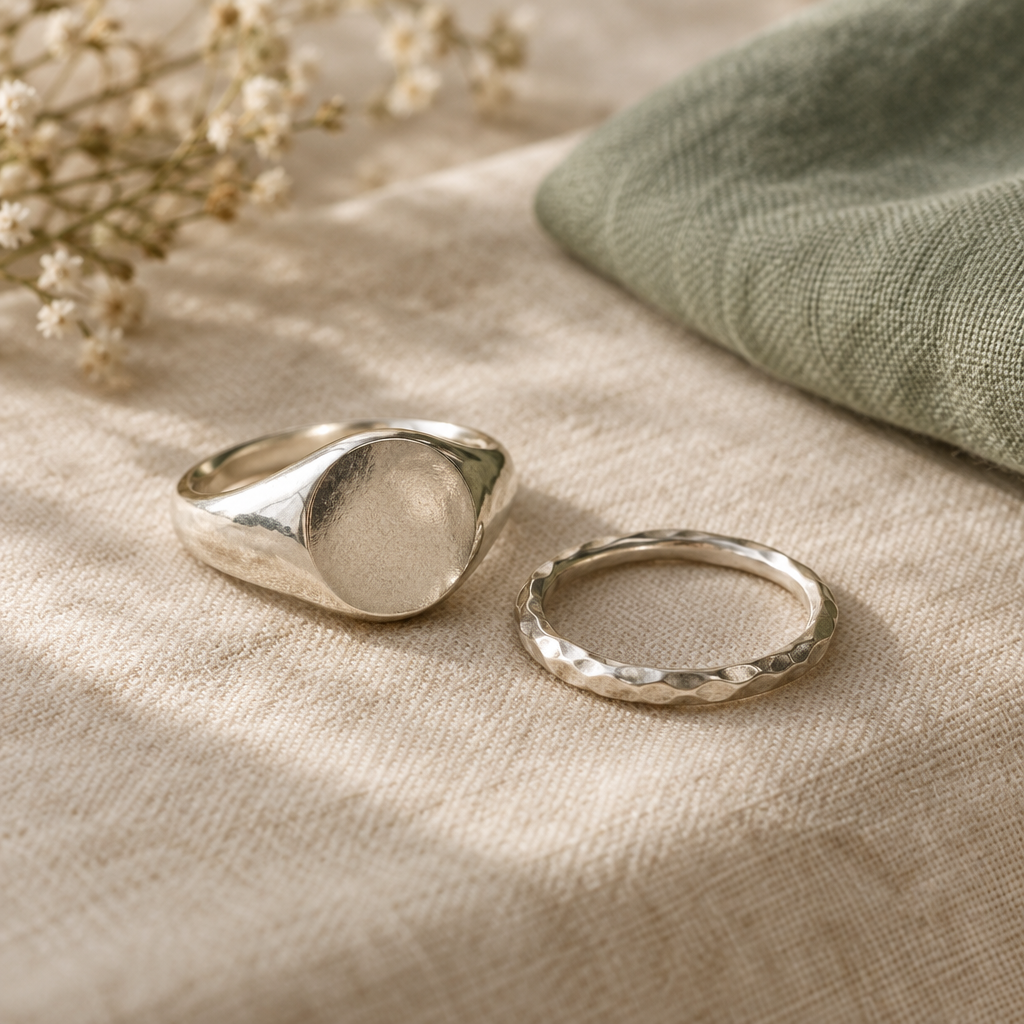 Two softly sculpted sterling silver rings resting on warm cream linen