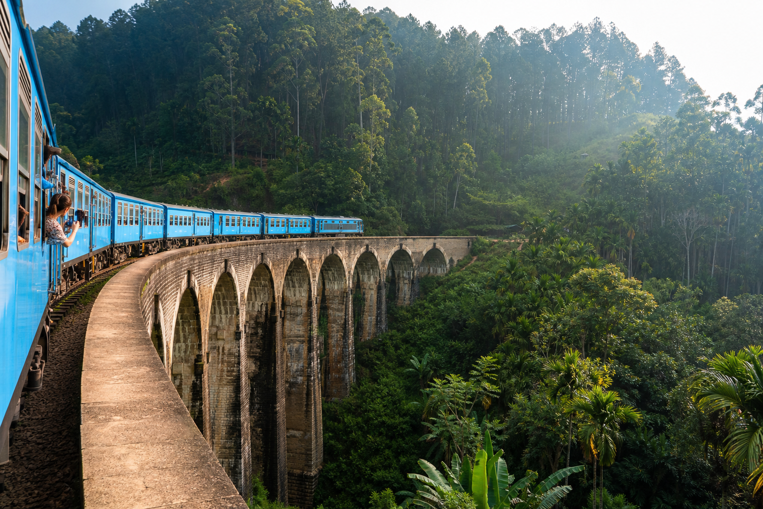 Blue train curving across the Nine Arch Bridge in Ella with lush jungle-covered hills