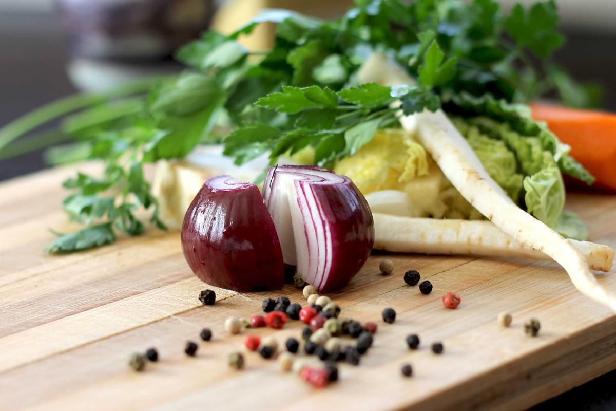 Red onion and peppercorns on a rustic wooden board
