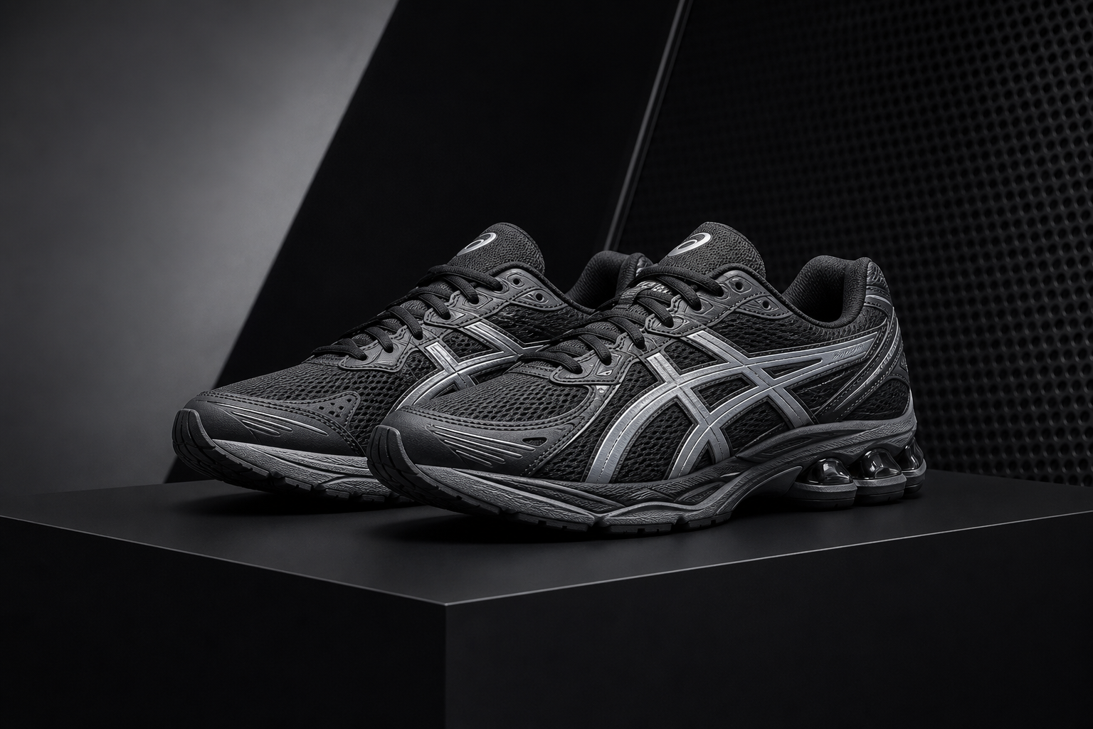 Modern Asics running shoes in dark gray with subtle silver panels placed on a matte black platform