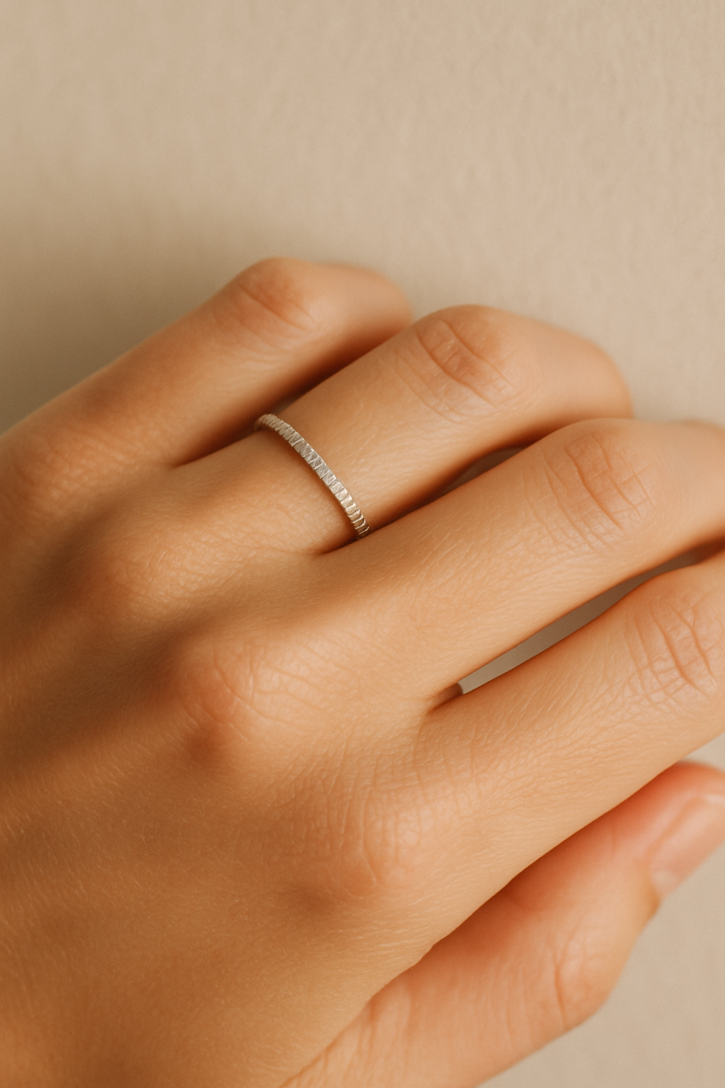 Close-up of a hand wearing a delicate handmade silver ring with organic texture, soft natural light