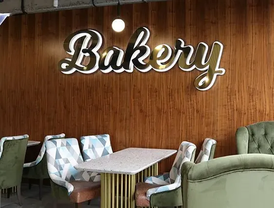 Interior bakery seating with wood-paneled wall and illuminated Bakery sign