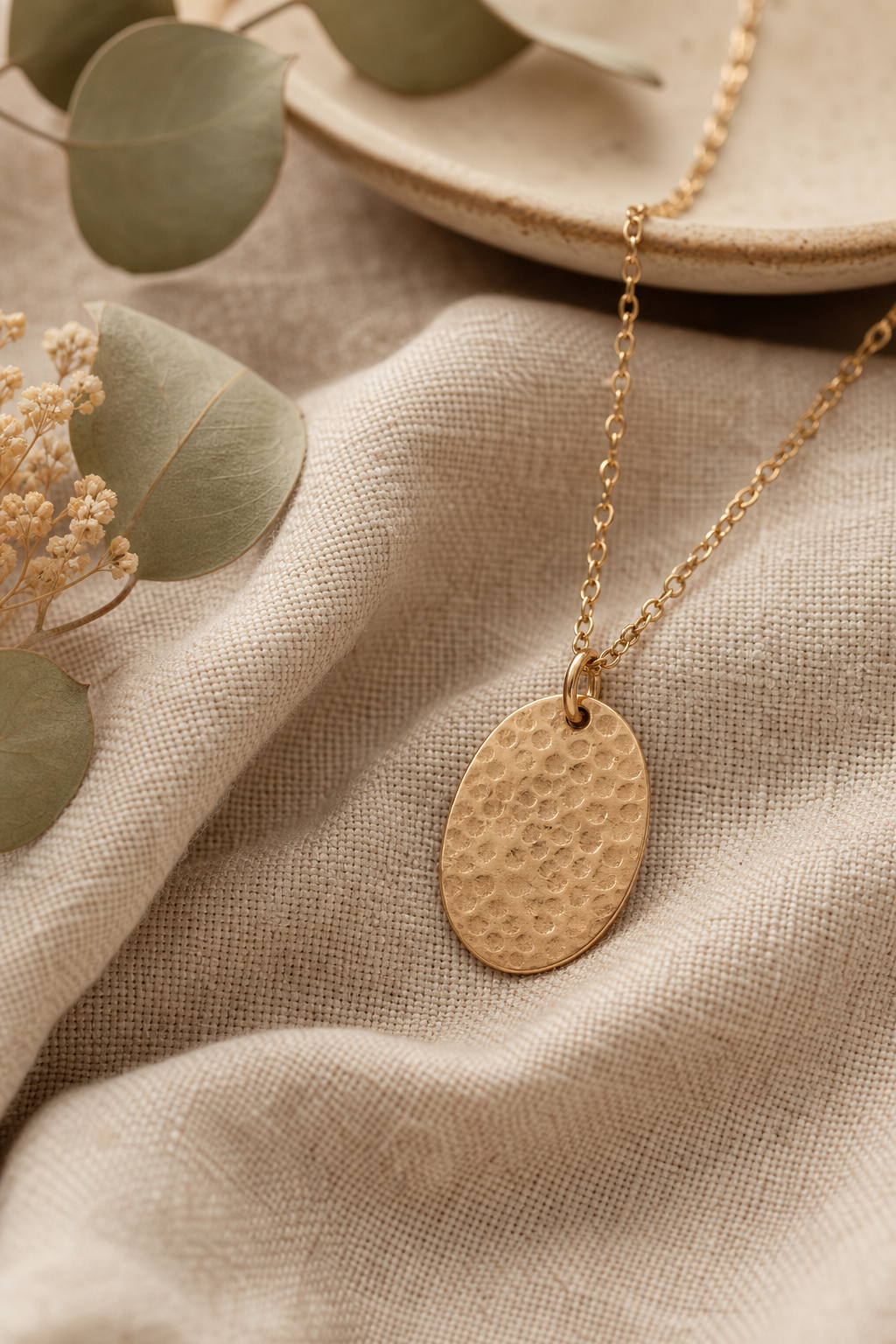 Warm-toned necklace with a hammered pendant on soft linen