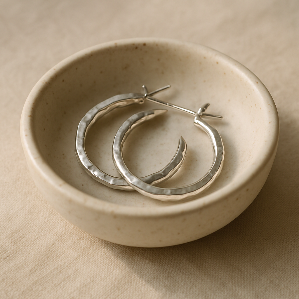 Pair of hammered hoop earrings resting on a ceramic dish