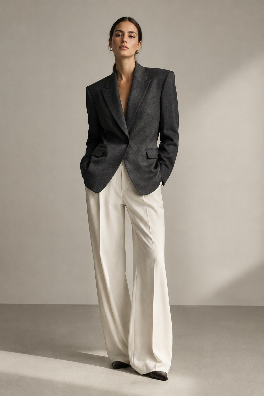 Model wearing a structured charcoal blazer in a minimalist studio