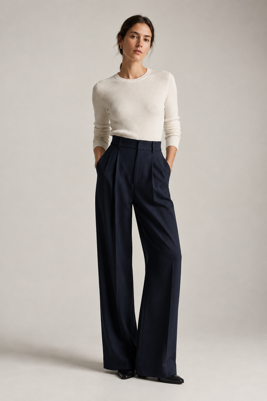 Wide-leg navy trousers with a crisp front pleat on a standing model