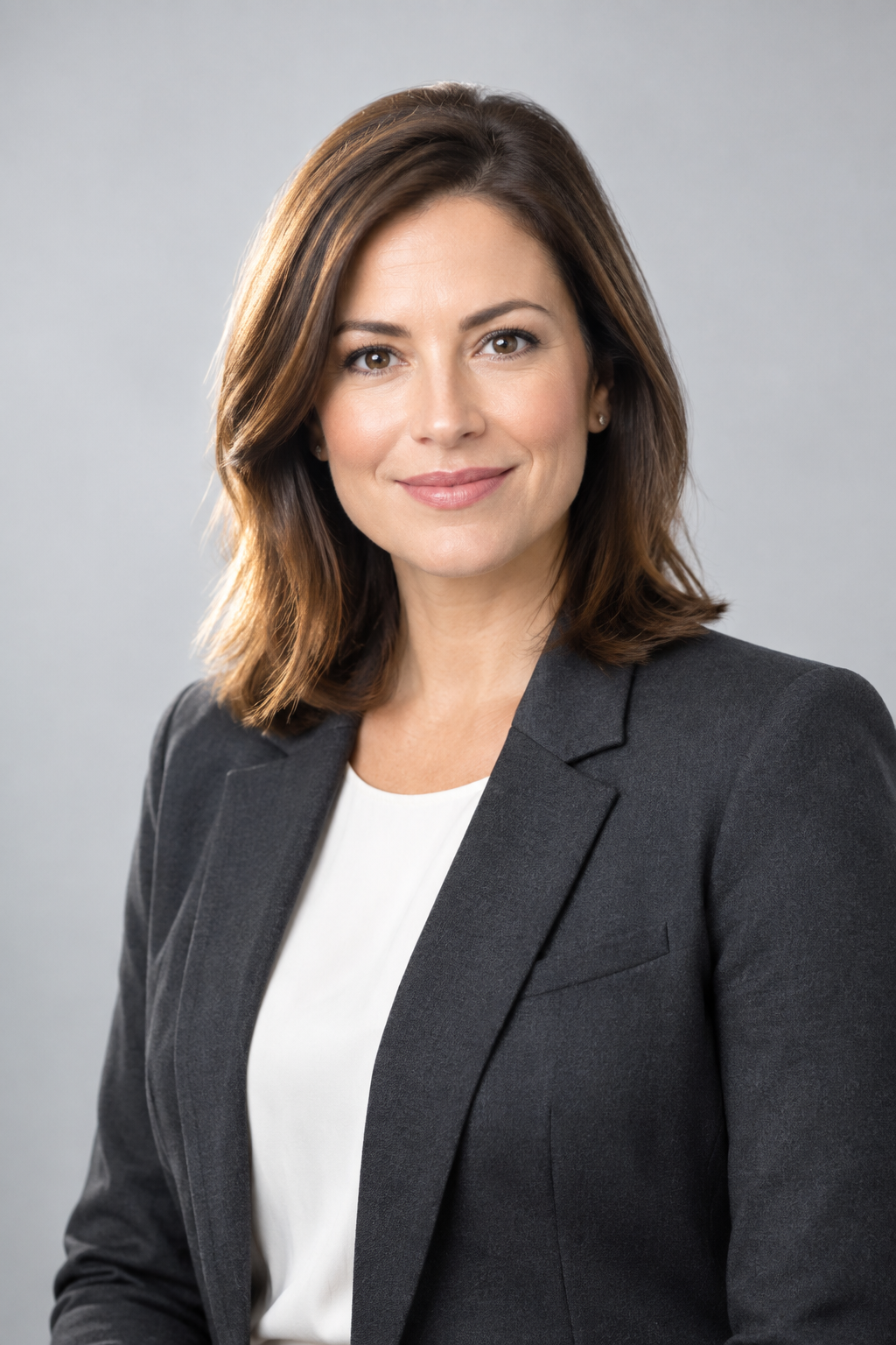 Strategy director wearing a charcoal blazer, professional portrait with soft light and light gray backdrop