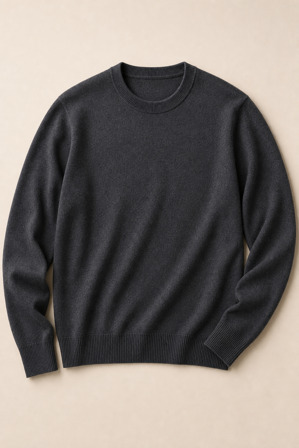 Charcoal crewneck knit sweater folded on a neutral studio surface