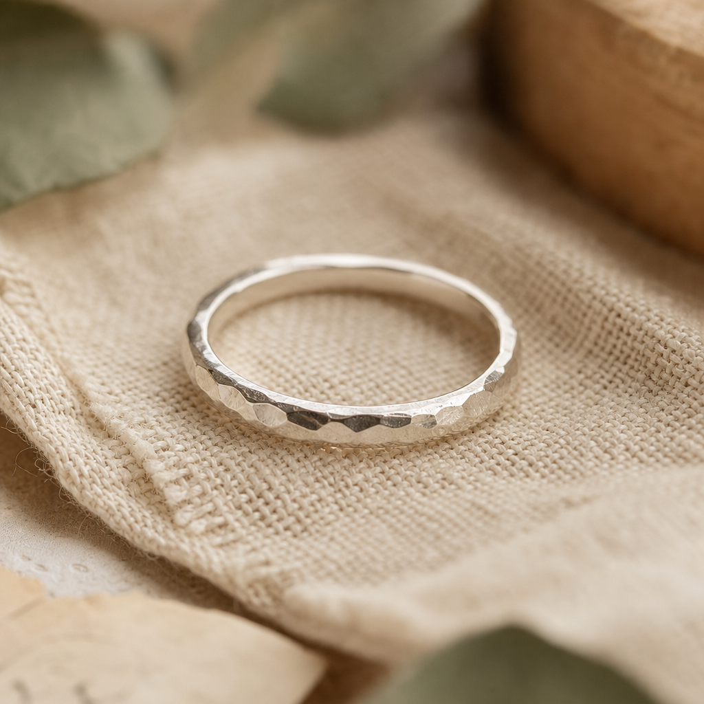 Macro close-up of a handcrafted sterling silver ring resting on natural linen fabric