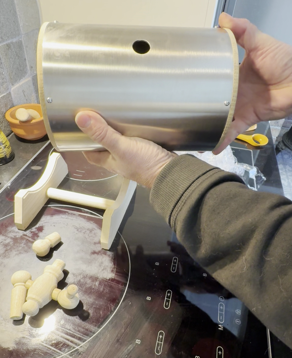 Brushed metal cylinder body with mounting hole shown by hand, documenting shell finishing details