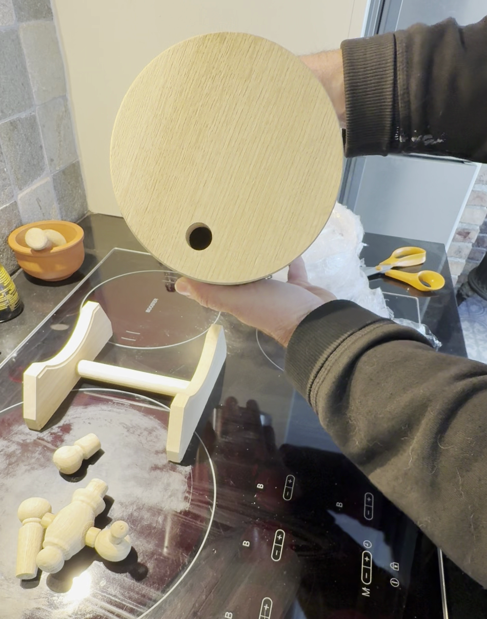 Round wooden end cap being held for fit and geometry checks in a workshop setting