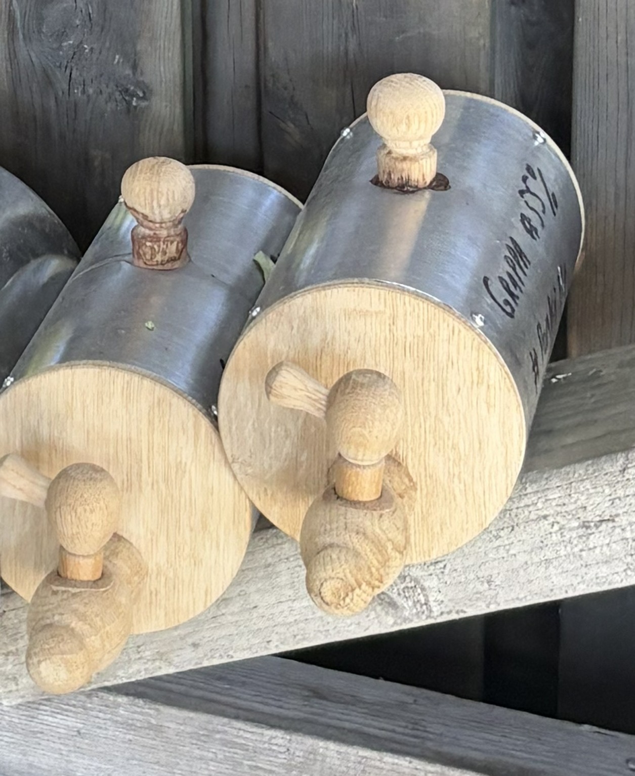 Two finished mini hybrid barrels resting on weathered wood, showing patina and final form