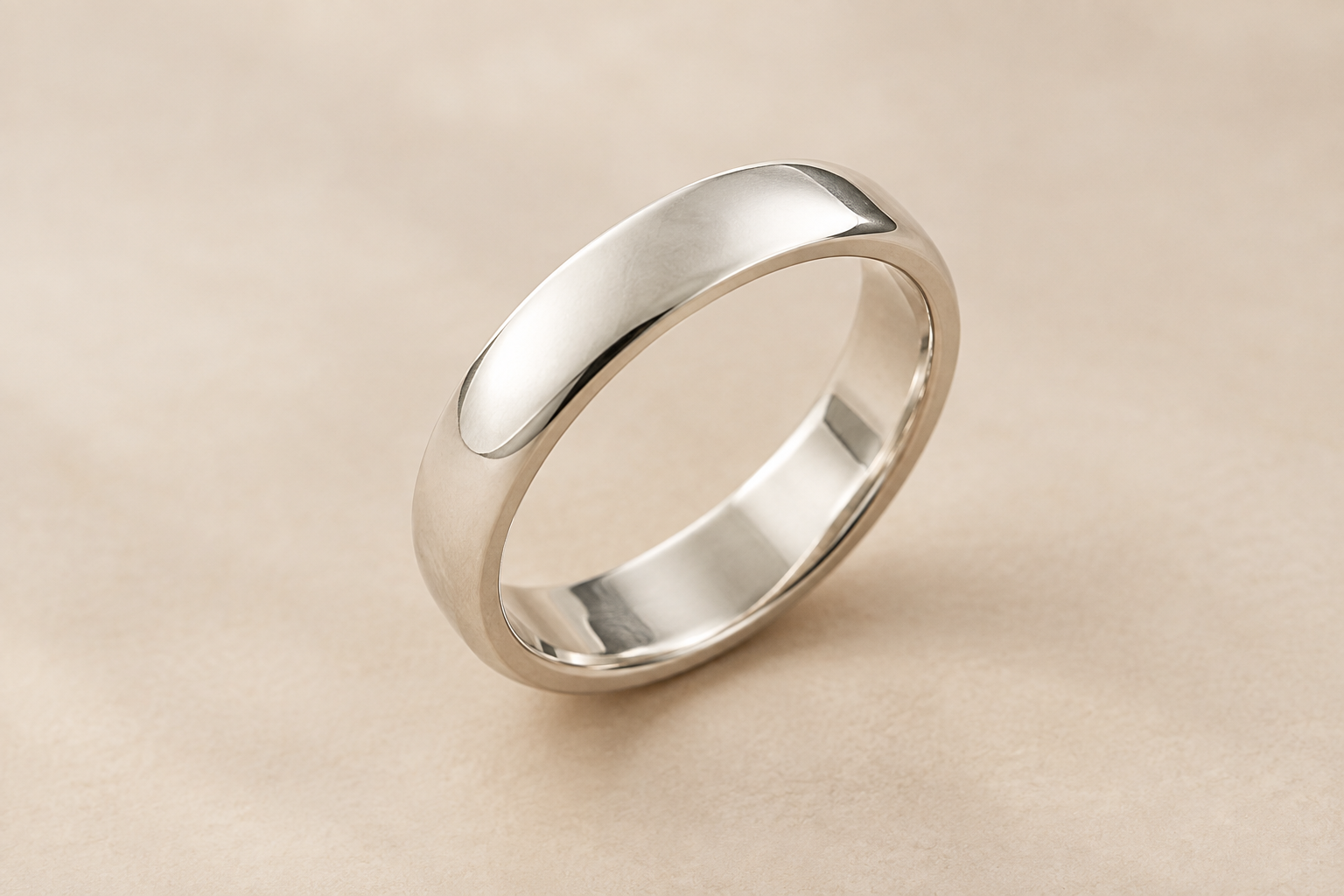 Polished silver ring on a soft neutral studio background, angled to show the outer band