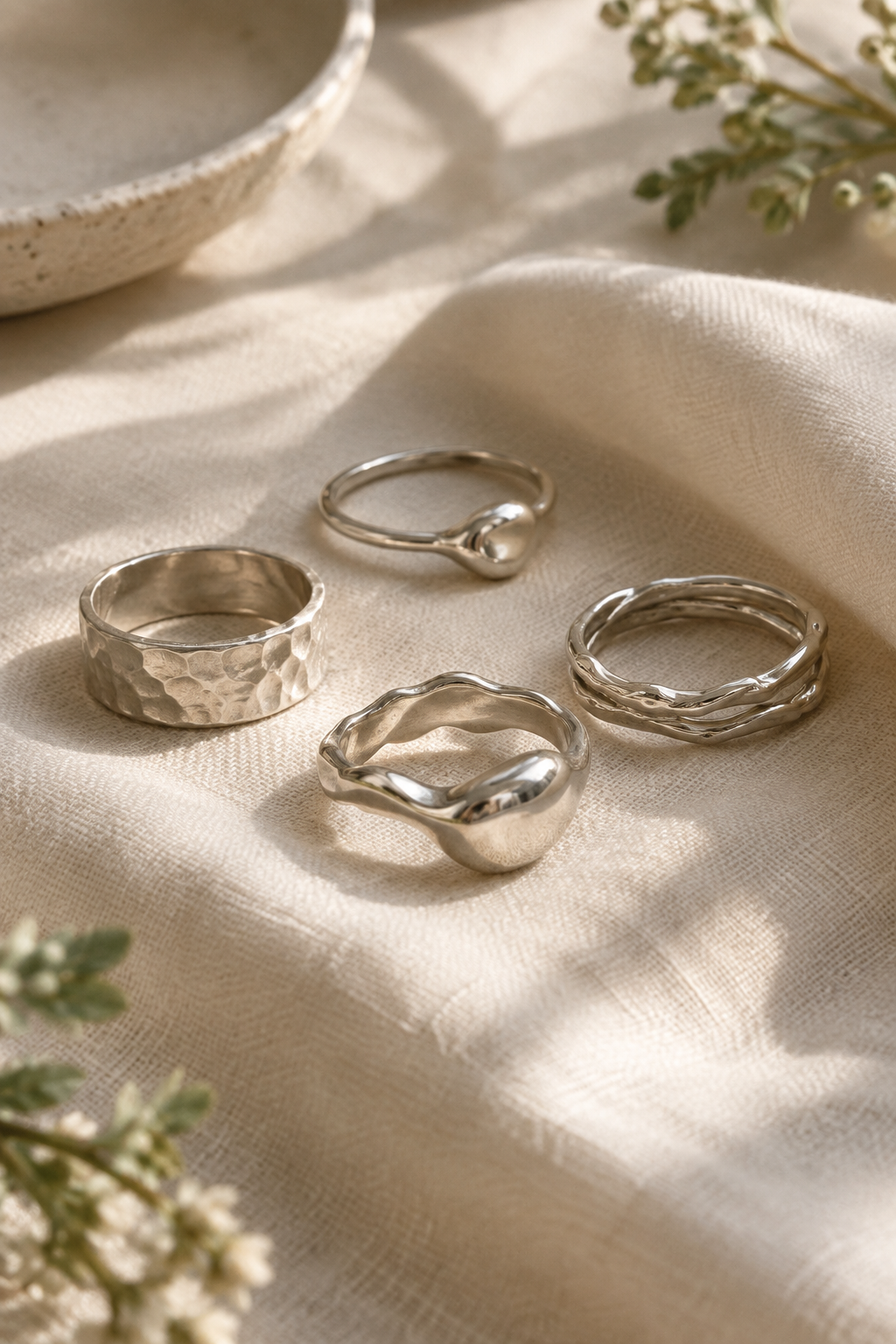Close-up of handmade silver rings styled on soft neutral fabric