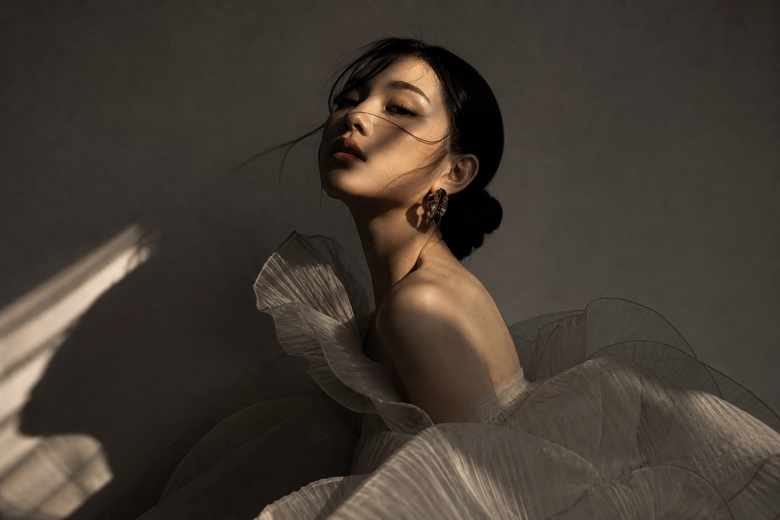 Portrait subject with sculptural shadows and layered fabrics, styled in an avant-garde concept