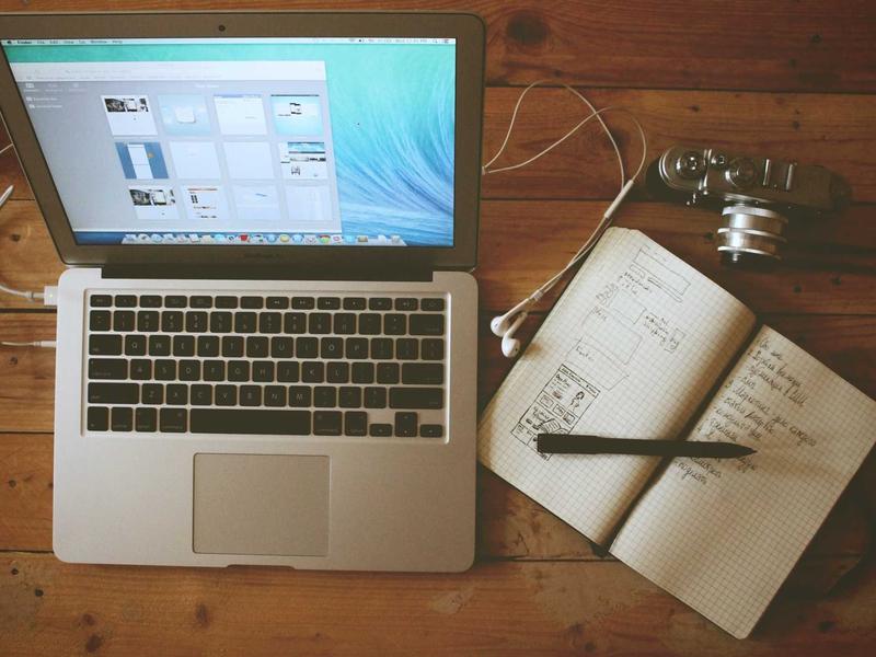 Laptop and notebooks on a wooden desk used for reviewing the bakery books
