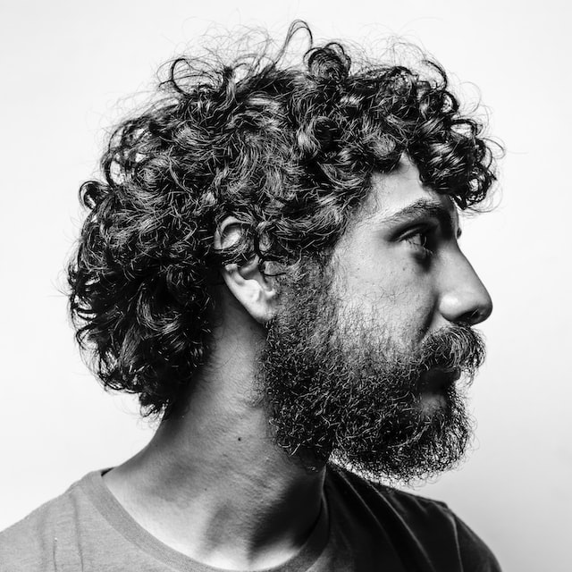 Black and white portrait of a smiling bearded man with curly hair