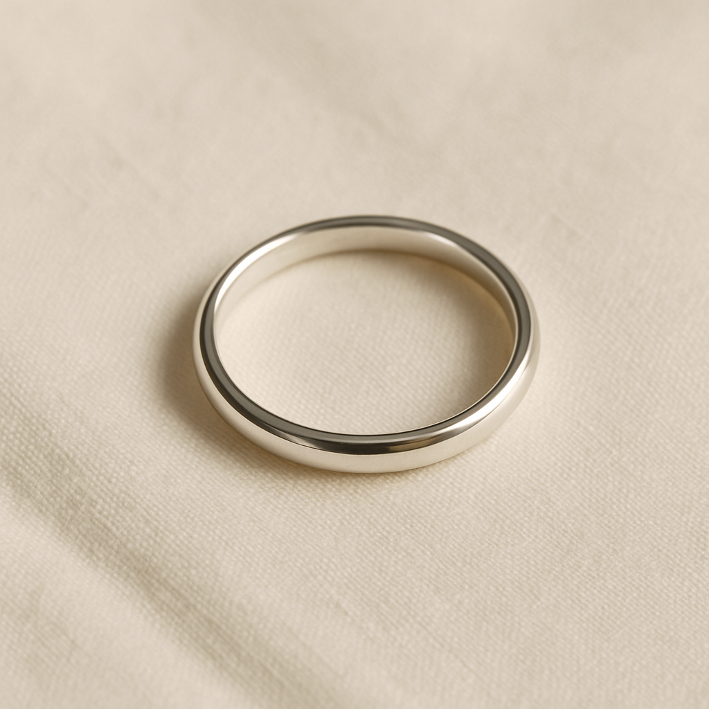 Polished slender sterling silver band on ivory linen