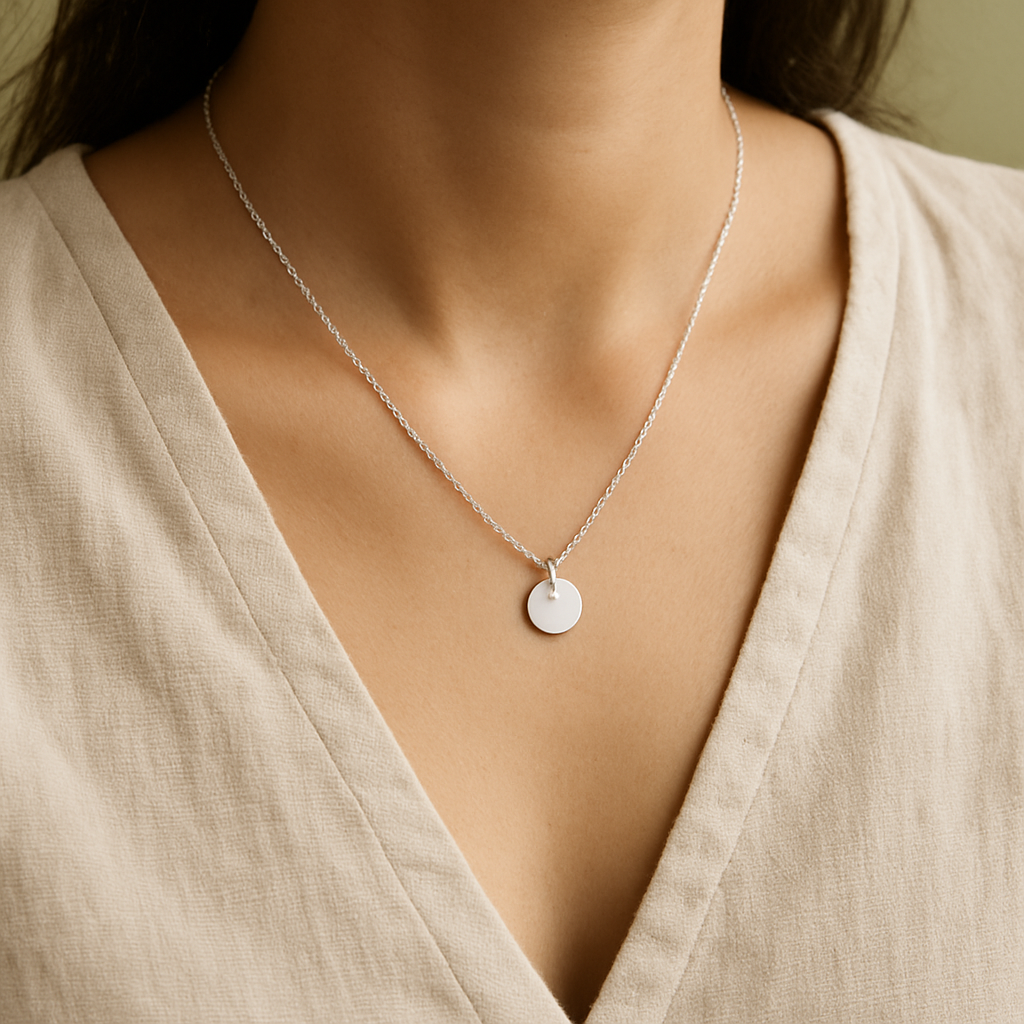 Silver pendant necklace styled over an oatmeal blouse