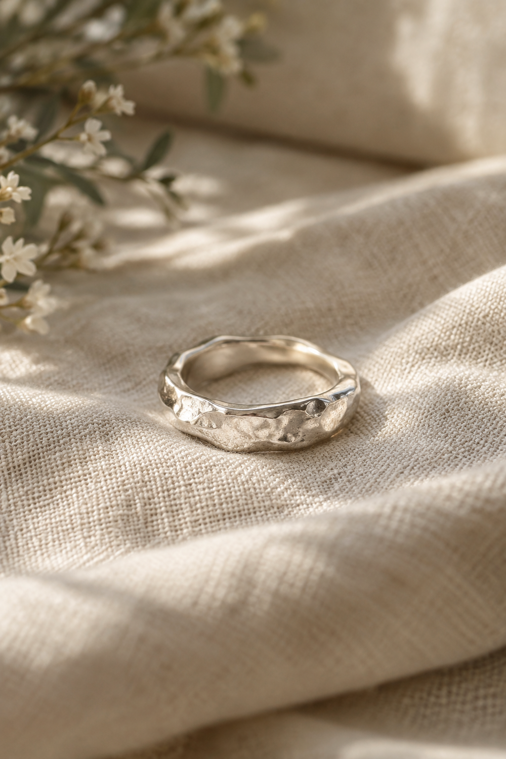 Hand-hammered sculptural sterling silver ring resting on warm linen