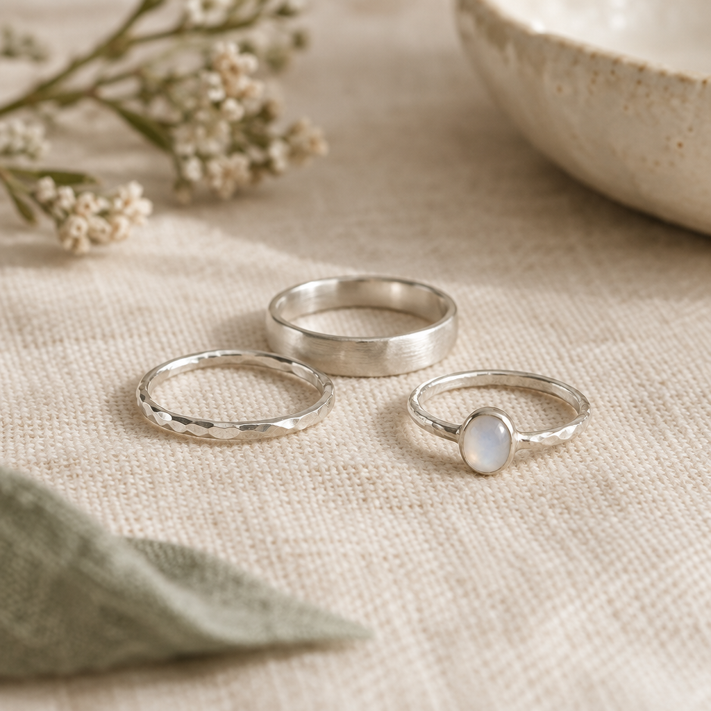 Hand-hammered silver rings resting on warm ivory linen