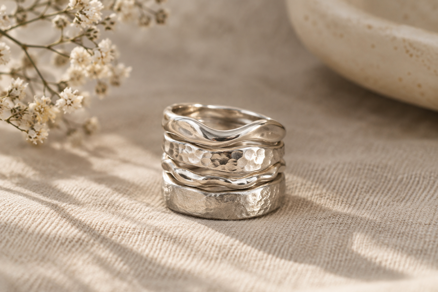 A sculptural stack of polished sterling silver rings with softly irregular artisan textures