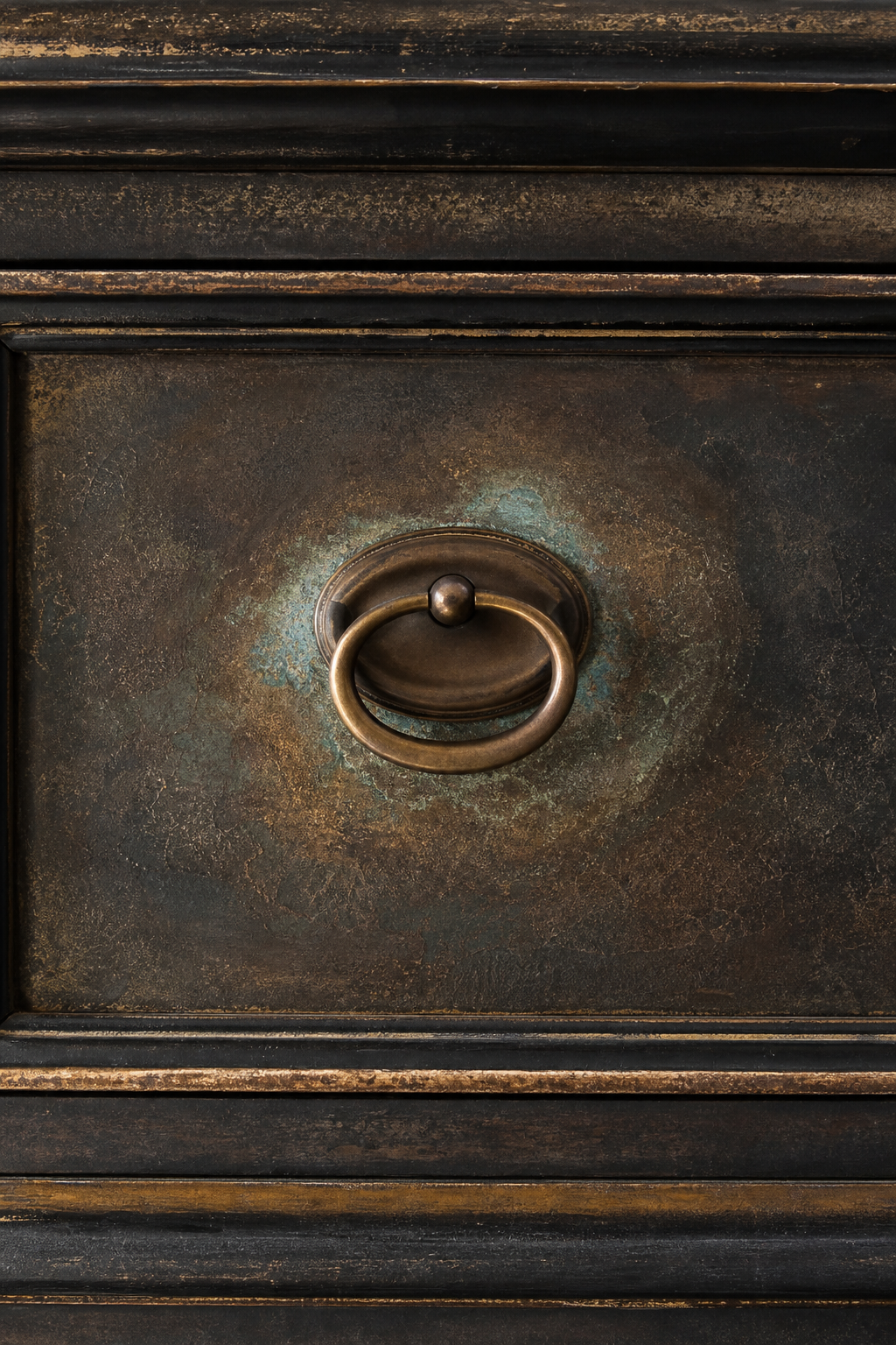 Detail shot of drawer front with aged bronze pull and nuanced patina layering around hardware