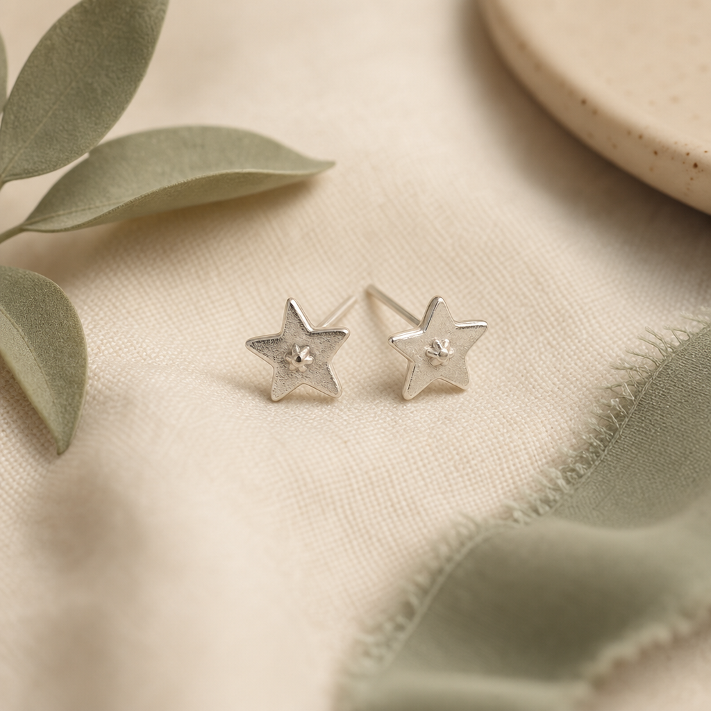 Minimal silver studs with tiny hand-shaped star detail.
