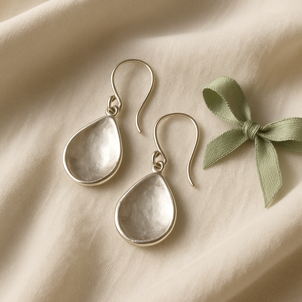 Pair of artisan silver drop earrings displayed on soft fabric