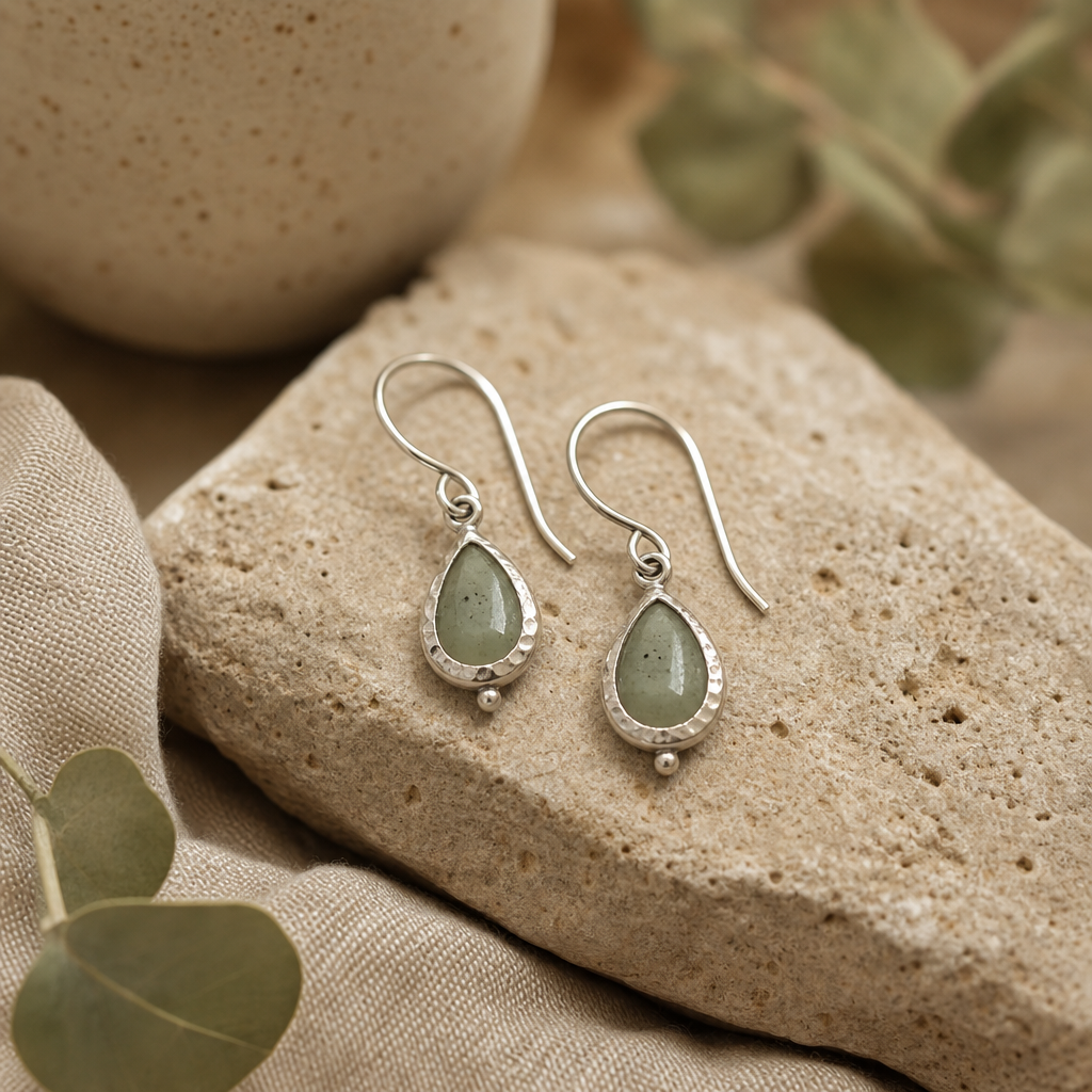 Small sage-toned stone drop earrings with hand-textured silver settings on natural stone