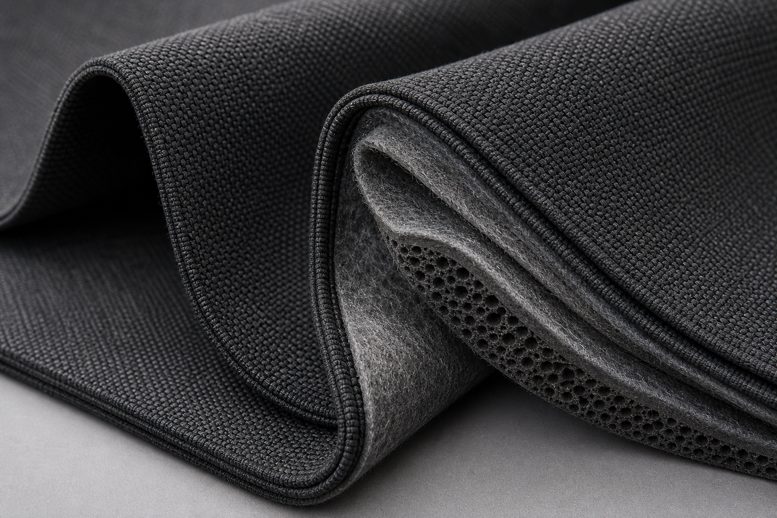 Close-up of dense charcoal acoustic curtain fabric with layered core structure for sound damping
