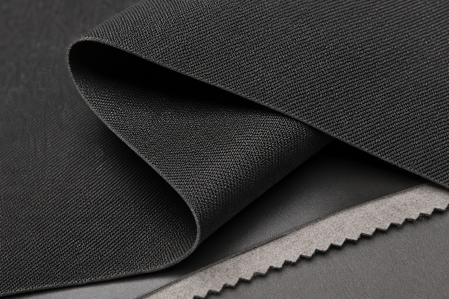 High-detail image of dark graphite coated blackout textile with subtle twill face and dense backing