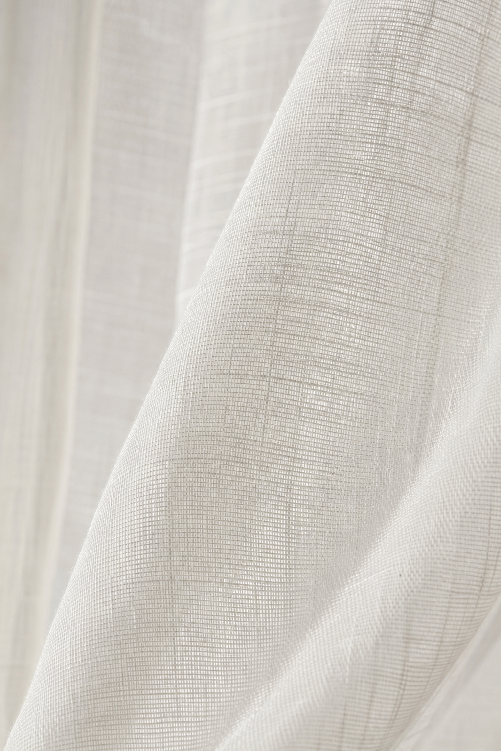 Close-up translucent inherently flame-retardant woven fabric with fine sheer texture in soft white tones