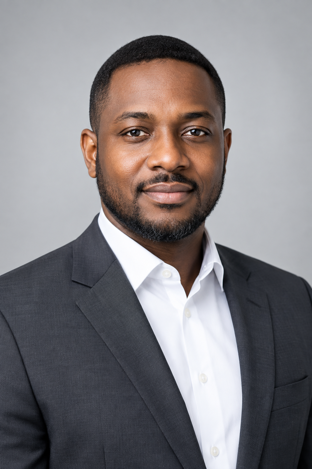 Refined executive portrait of Adebayo Ologunja in a charcoal suit and white shirt, with soft even lighting and a polished neutral corporate backdrop