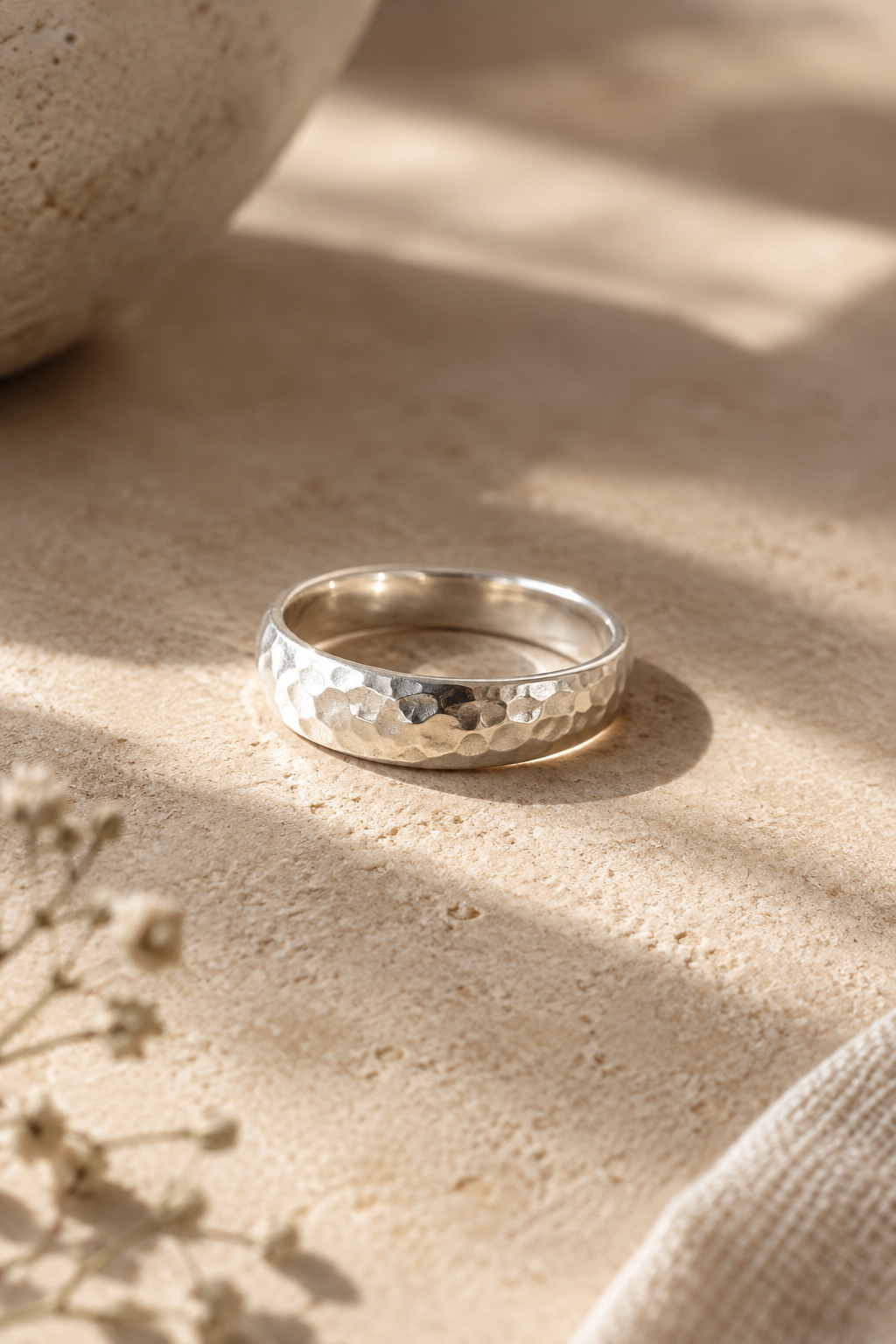 Handmade sterling silver ring with a softly hammered finish on a warm neutral surface