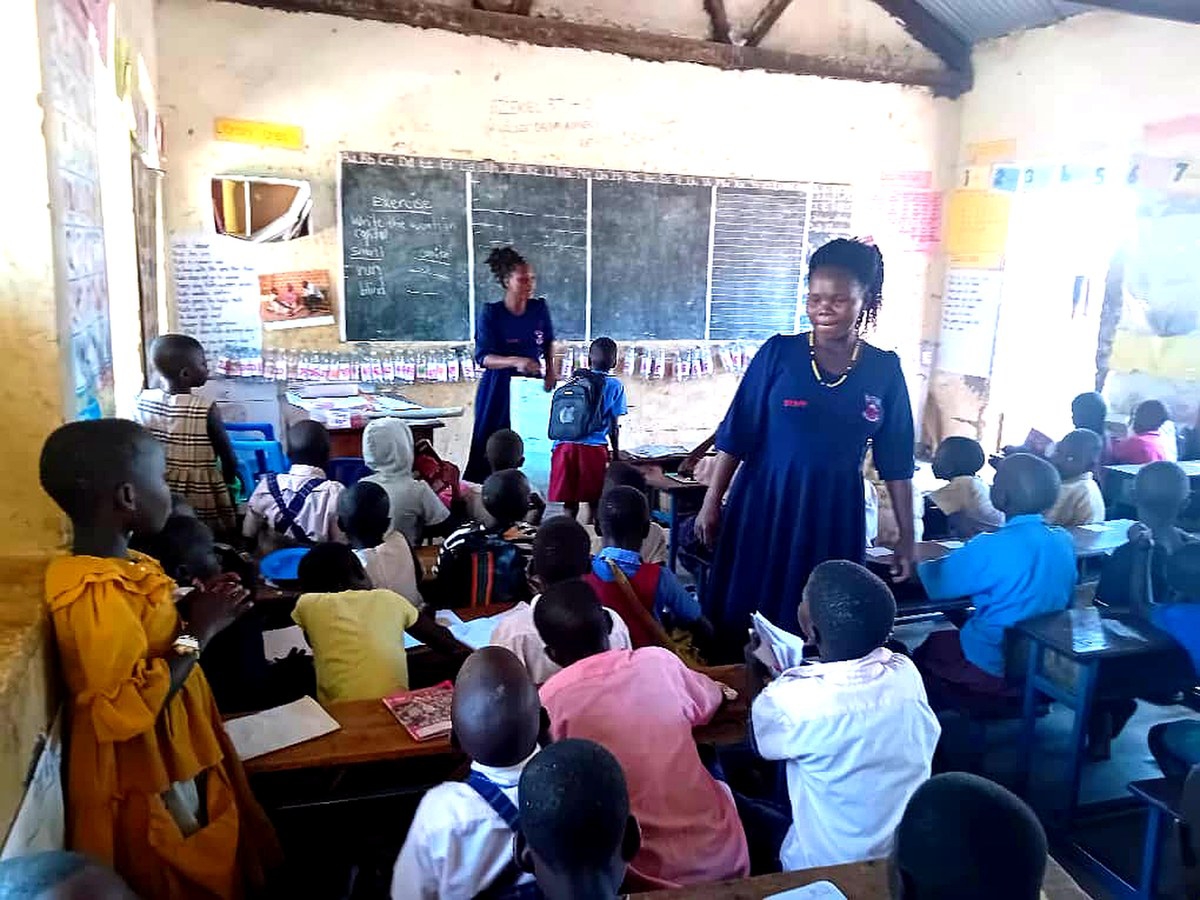 Community facilitators, girls, and caregivers in Paidha, Zombo District, Uganda participating in a school-based outreach session on girls’ education, menstrual health, and child protection
