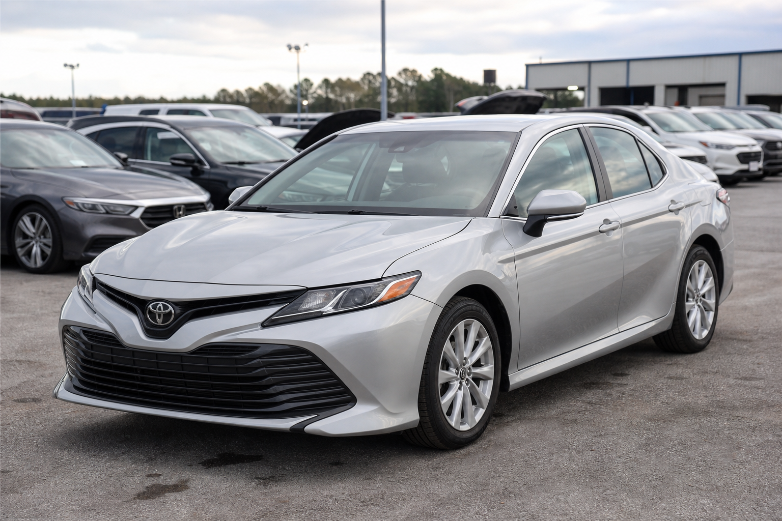 Silver Toyota Camry sedan parked at an outdoor auction lot with soft daylight