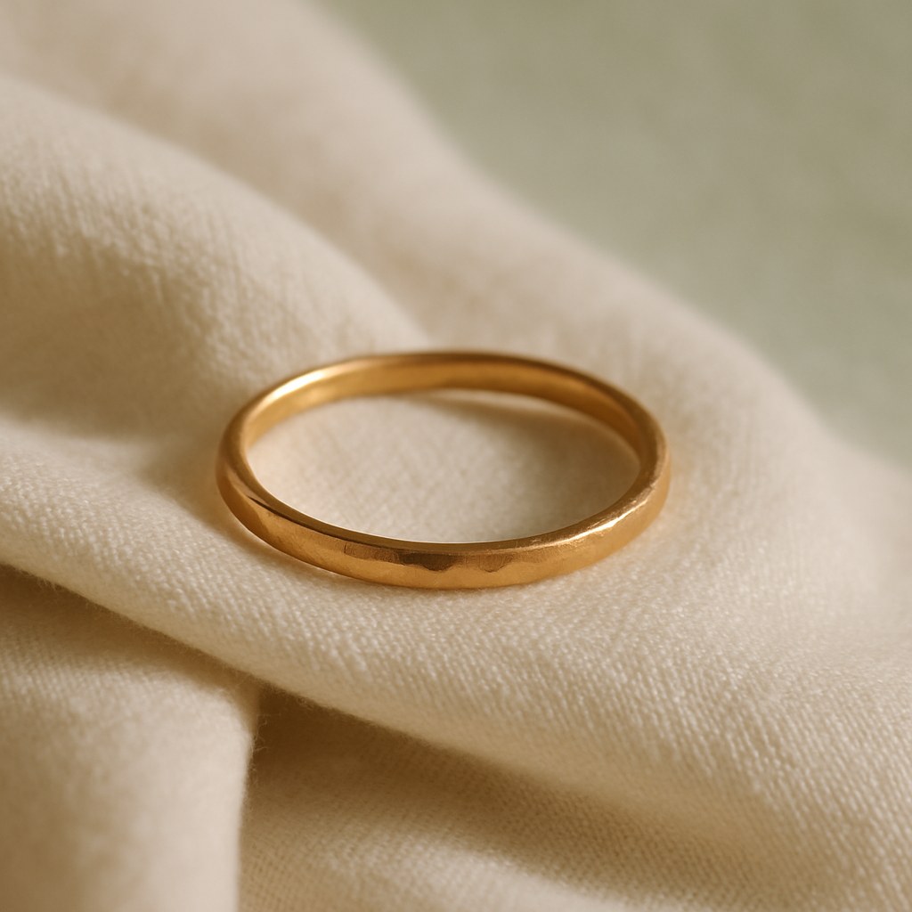 Close-up of a delicate gold band ring resting on soft linen fabric in warm natural light