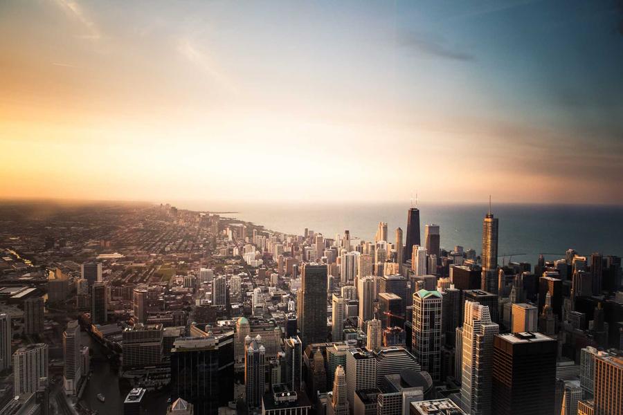 City skyline at sunset with tall buildings and a warm orange sky