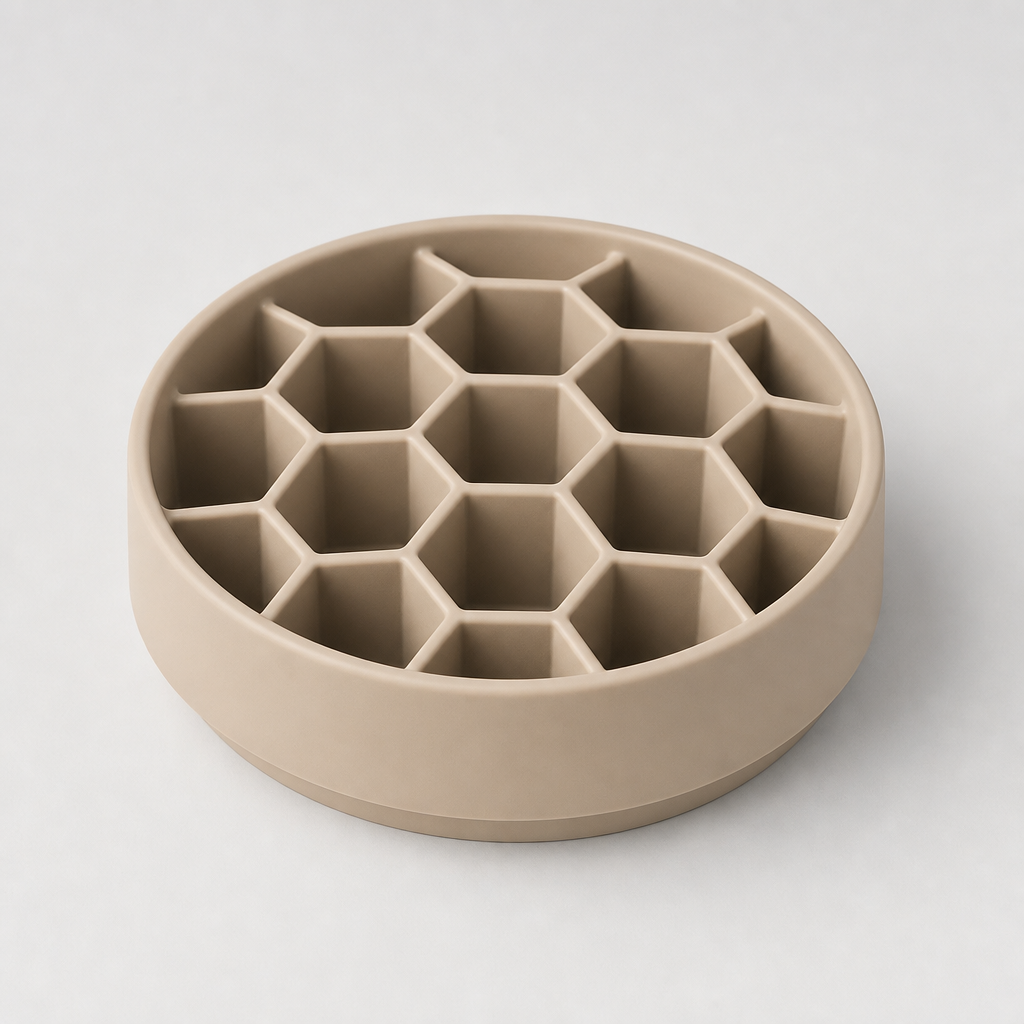 Honeycomb silicone slow feeder bowl in warm stone beige with hexagonal wells, photographed on a clean light gray background.