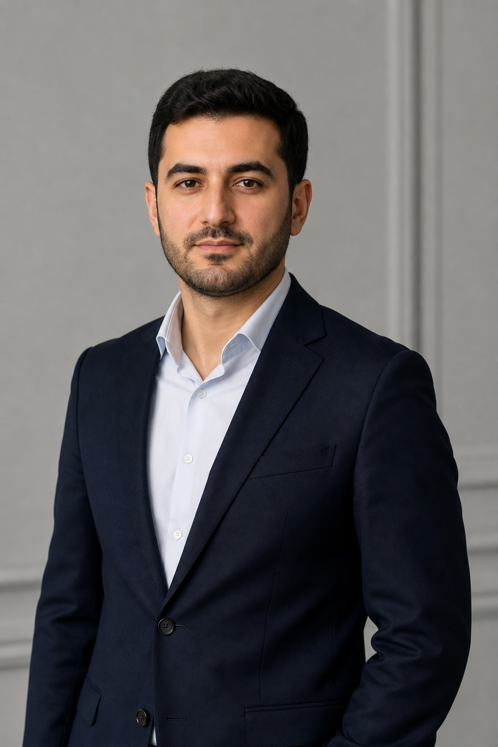 Rasim in a dark blazer, seated professional portrait with clean studio lighting and neutral background