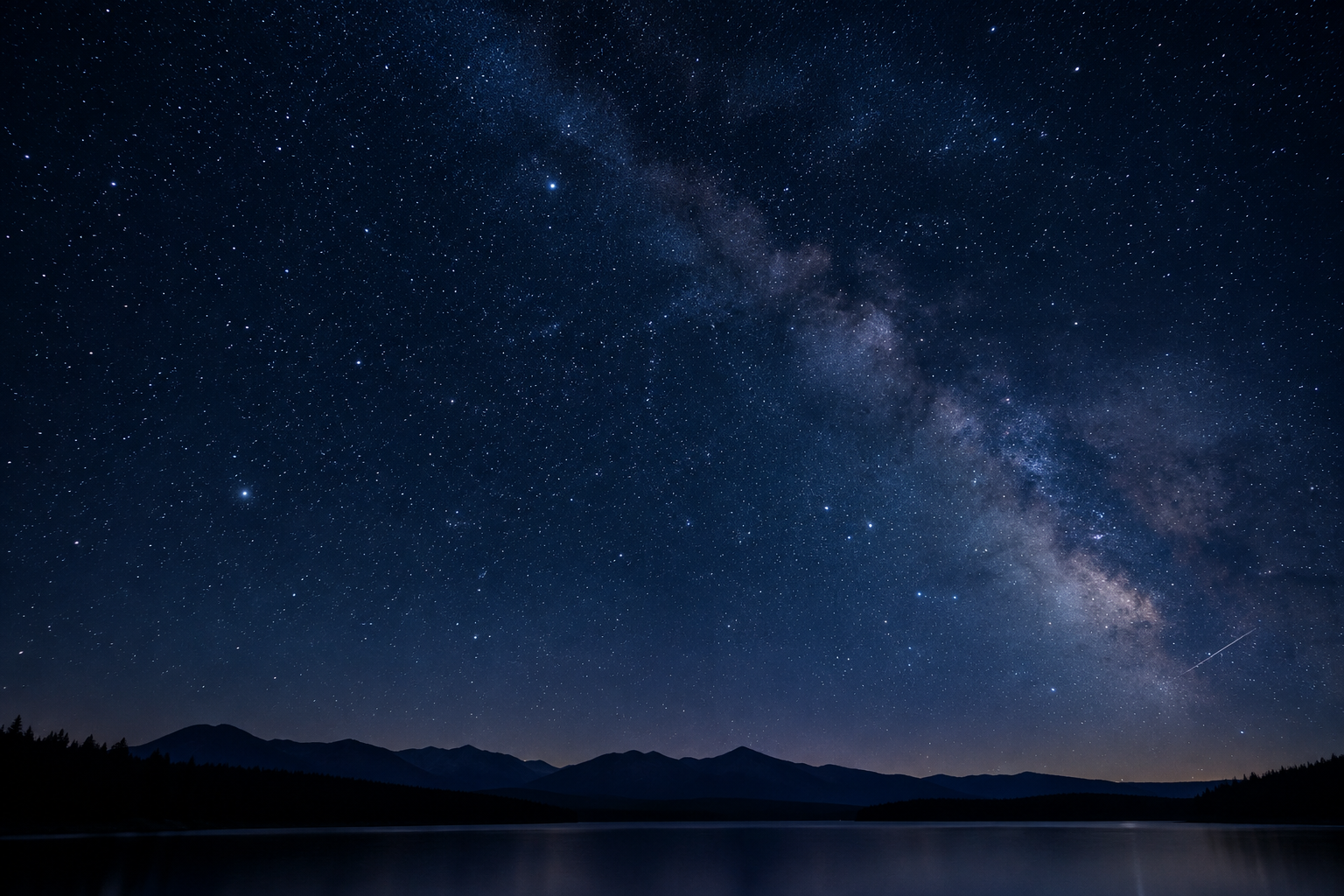 Wide atmospheric night sky with dense stars and faint milky haze above a dark horizon