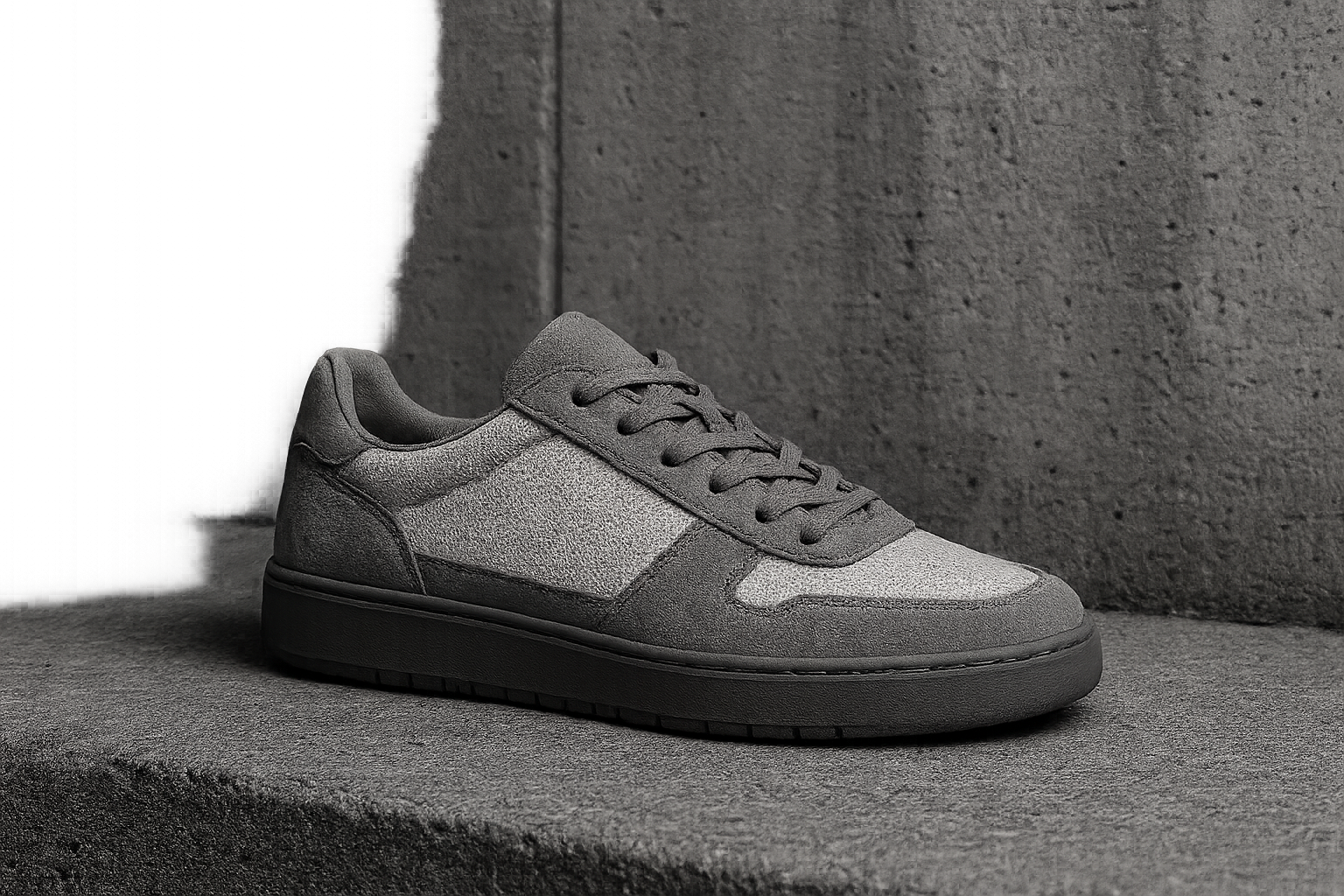 Concrete Runner low-top sneaker in cool gray suede and white mesh photographed against a textured concrete wall