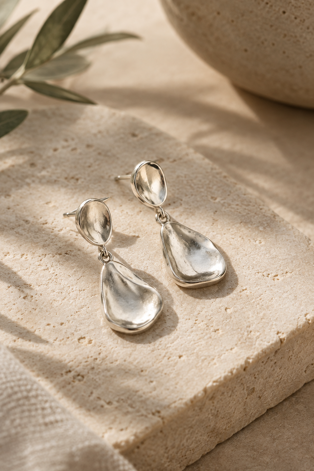 Pair of sculptural handmade silver earrings in a close-up studio portrait