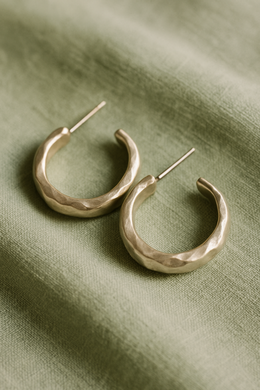 Pair of handcrafted silver hoop earrings on a soft sage backdrop