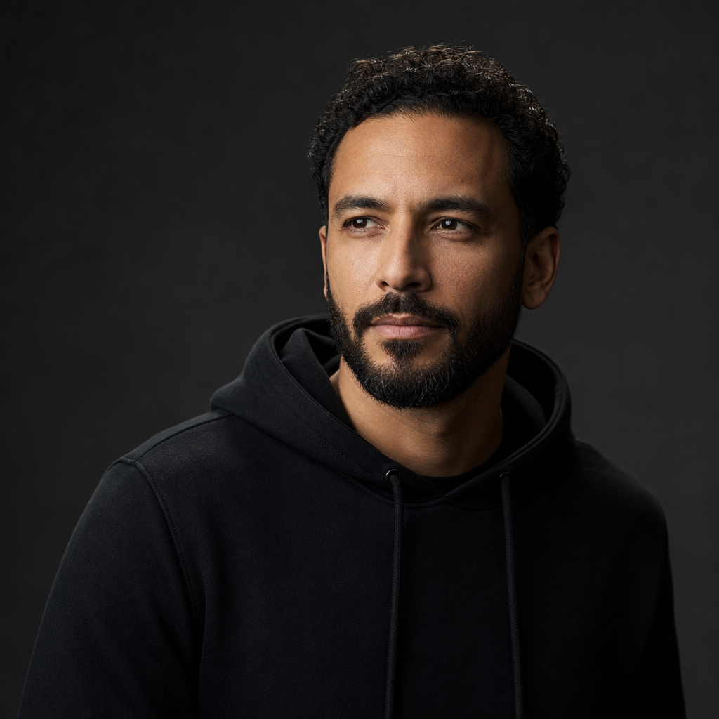 Portrait of Marcus Lee, a man with short curly hair and a trimmed beard wearing a dark hoodie